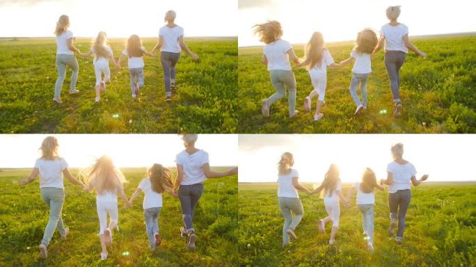 友情概念。年轻快乐的妇女与他们的女儿跑过田野在日落