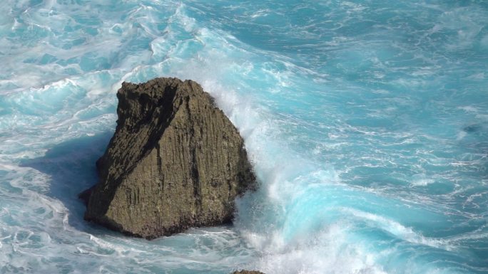 慢动作关闭: 湍流泡沫海浪打破尖锐的岩石礁。汹涌的桶波击中岸边飞溅浅滩。强大的冲浪打破撞击岩石喷洒水