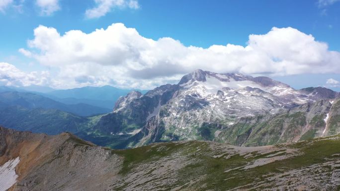 在岩石悬崖、冰川和雪峰之间的山脊空中拍摄的照片。令人惊叹的山景鸟瞰.