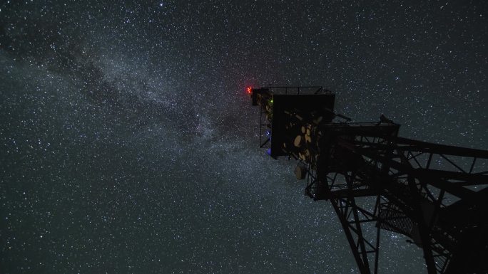银河星系在星空夜的流逝中飞过通讯塔