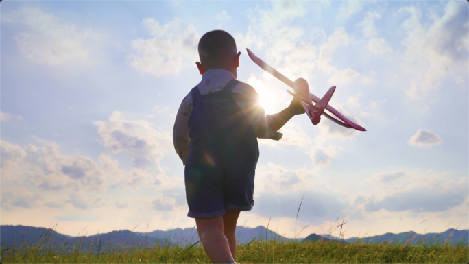 小男孩拿着飞机模型在山顶奔跑玩耍梦想起飞