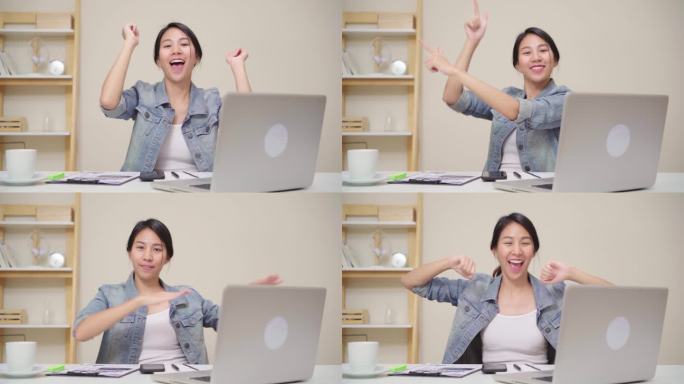 年轻的亚洲妇女在家里客厅的办公桌上使用笔记本电脑工作。亚洲女商人成功庆祝在家庭办公室快乐跳舞的感觉。