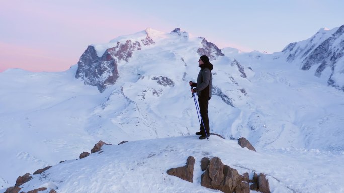 男子与登山棒站在山顶，俯瞰景观