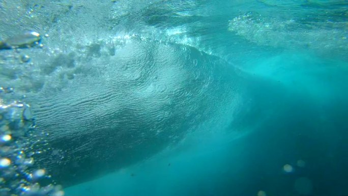 水下慢动作：水晶般清澈的桶波在深海中冲破相机。相机从富埃特文图拉阳光明媚的海滩下降到深晶莹的海水下巨