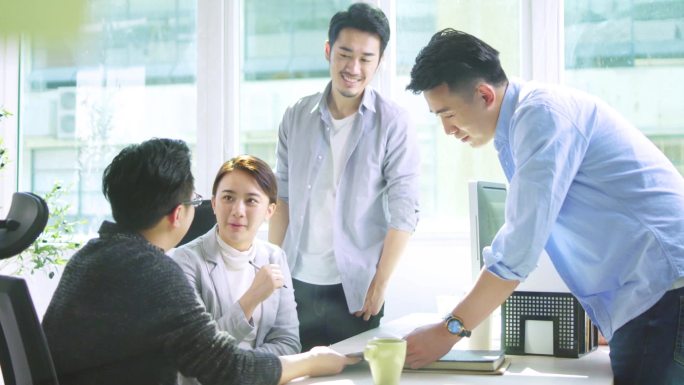 三个年轻的亚洲人讨论在办公室使用平板电脑的业务