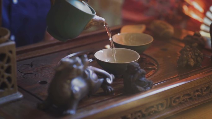 男子将绿茶由茶壶倒到盖旺的特写