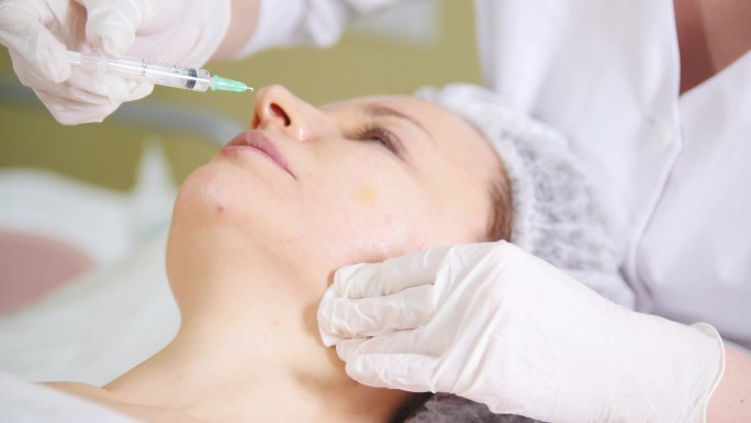 美容临床美容科医生在美容门诊患者面颊下注射中位治疗的美容手术.