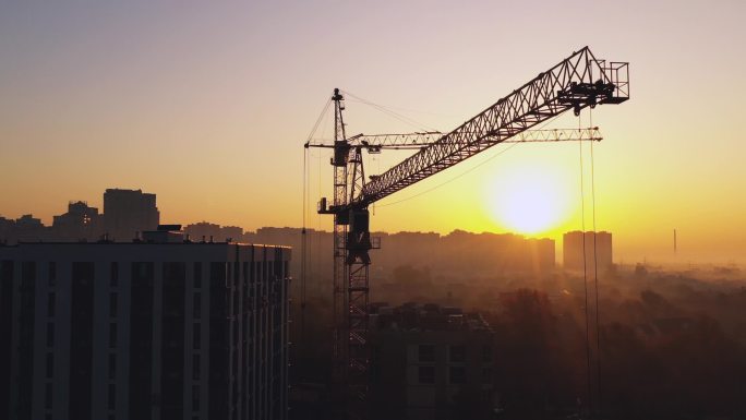 深红色天空背景下的建筑工地和起重机。