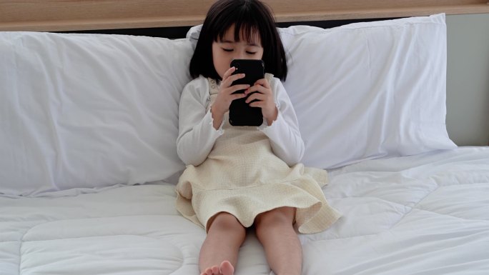 女孩在床上玩手机，社会问题导致儿童发育不良.