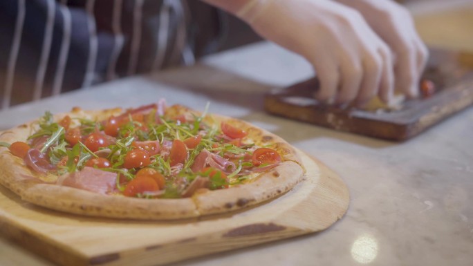 厨师用手将配料放在比萨饼上，然后在木板上撒上奶酪。烹饪披萨。烹饪披萨。