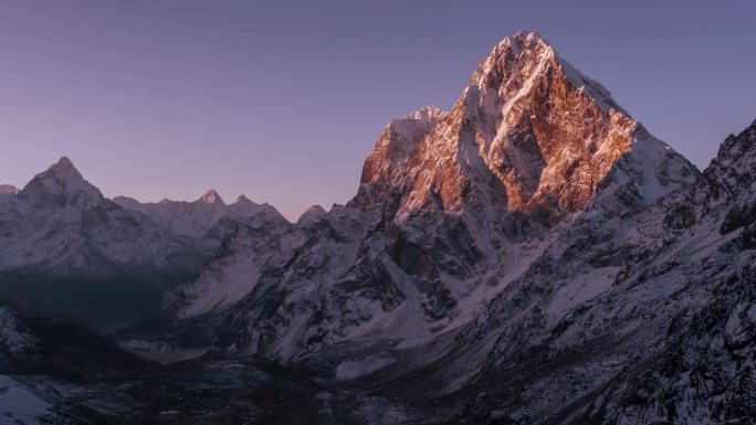 日出时Cholatse峰 (6501米) 岩石壁上的阳光运动。尼泊尔，喜马拉雅山山脉。时间失效。