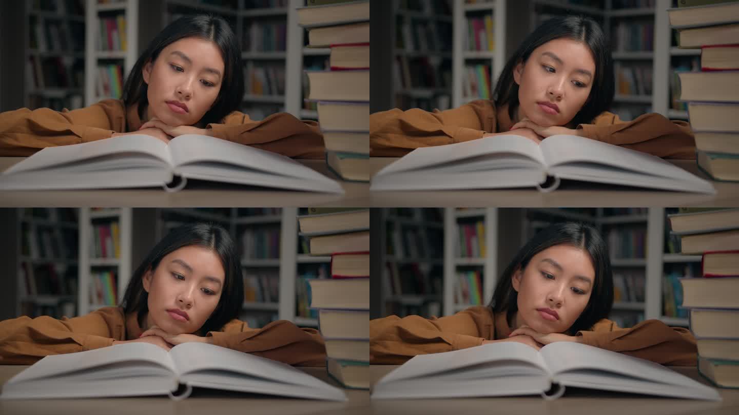 无聊悲伤疲惫懒惰的年轻韩国女子读无聊的书躺在大学图书馆的桌子上没有动力做作业的女学生为大学考试做准备