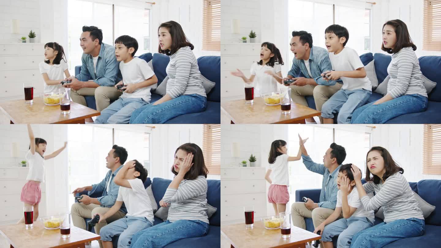 快乐的亚洲家庭爸爸，妈妈和孩子们在家里客厅里玩着技术控制台的电子游戏。自我隔离、待在家里、与他人保持