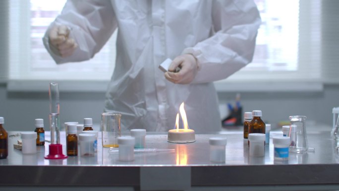 穿着防护工作服的人在实验室里点燃桌子上的物质