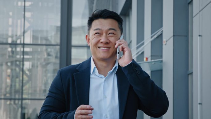 接近亚洲40多岁的商人企业家雇主男人走进市中心与同事们进行移动对话，用智能手机呼叫虚拟组织者