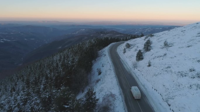 无人机沿着雪地雪地山路，靠近冰冻的常绿森林，全景尽收眼底