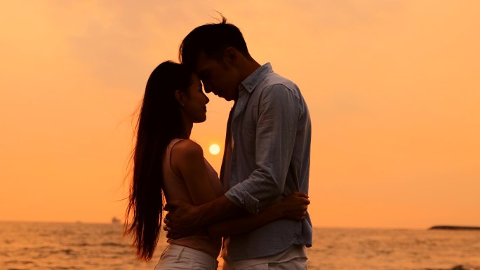 浪漫的年轻夫妇在夕阳西下的海滩拥抱