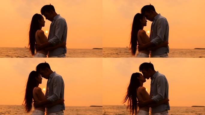 浪漫的年轻夫妇在夕阳西下的海滩拥抱