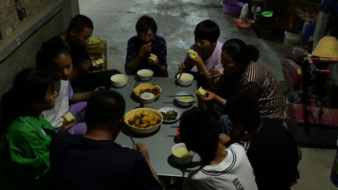 夜晚农民一家人围着桌子吃饭