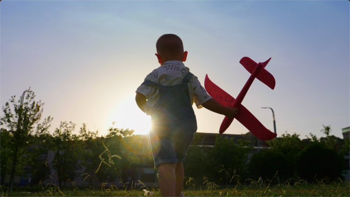 小男孩拿着飞机模型草地逆光奔跑飞翔的梦想
