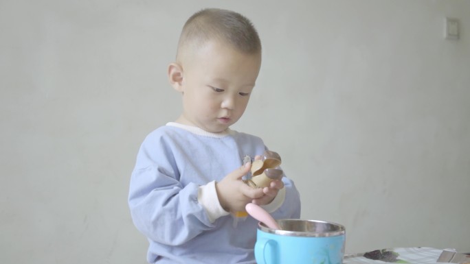 使用勺子学吃饭的小男孩幼童