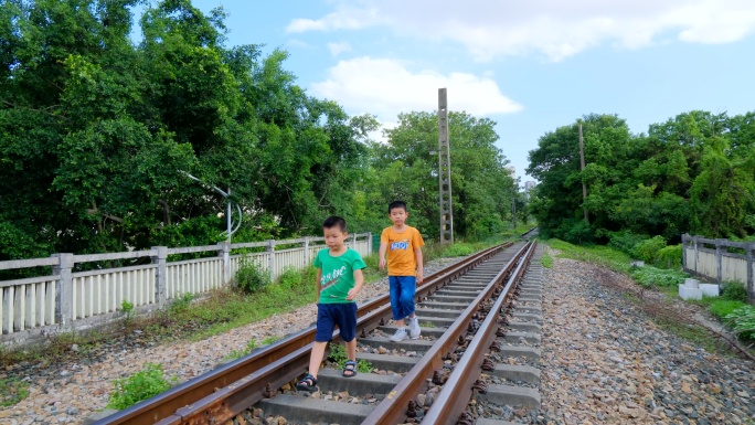 两个小孩走在铁路上玩耍