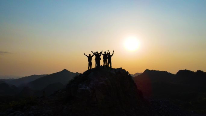 一群人站在山顶挥手呐喊团队精神登山攀登者