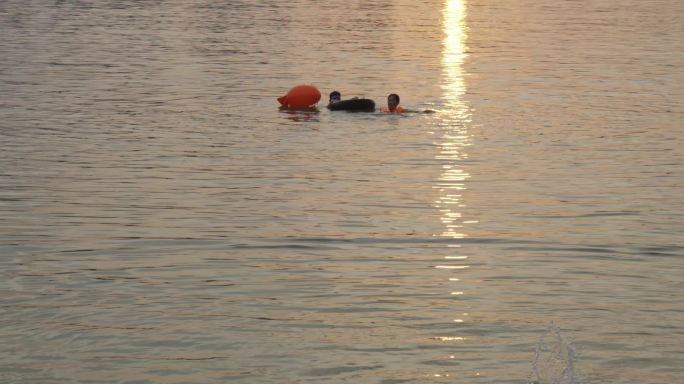 夕阳在江边游泳嬉水的小孩