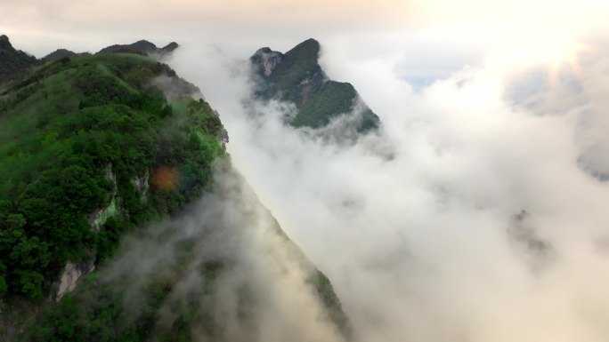 山顶云层翻山环绕阳光破开大雾照射森林