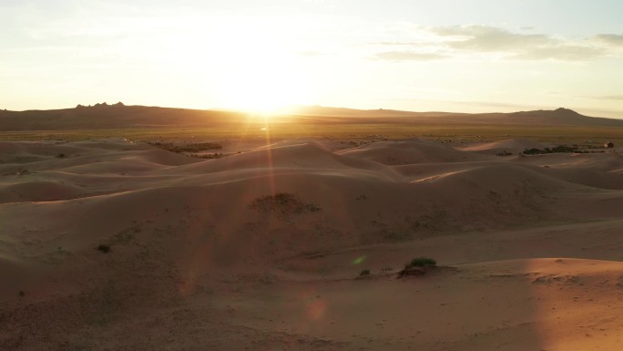落日笼罩在沙漠的沙丘上 