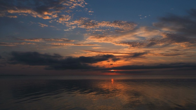 海上日出时间流逝，美丽的日出海洋，光滑的海水和充满活力的彩云，海上早晨的天空，日出时水面上美丽的倒影