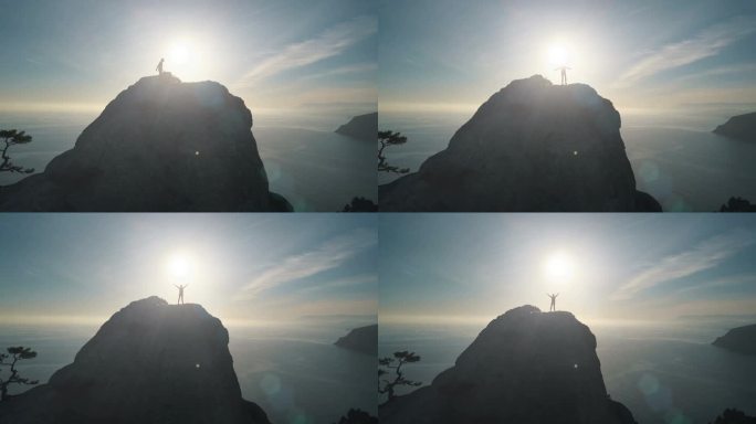 一个年轻女子在日落时分爬到山顶顶端的空中剪影。夫人在山顶上美丽的风景举起她的手.
