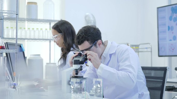 医学研究专家团队在现代实验室与科学家进行实验, 在计算机上工作, 在显微镜下观察物质