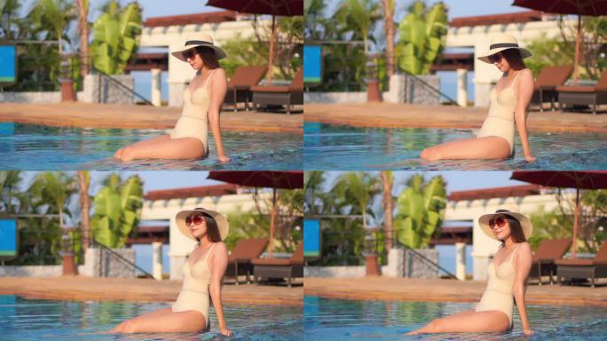 美丽的亚洲年轻女子在酒店度假胜地的游泳池周围放松一下，以便度假