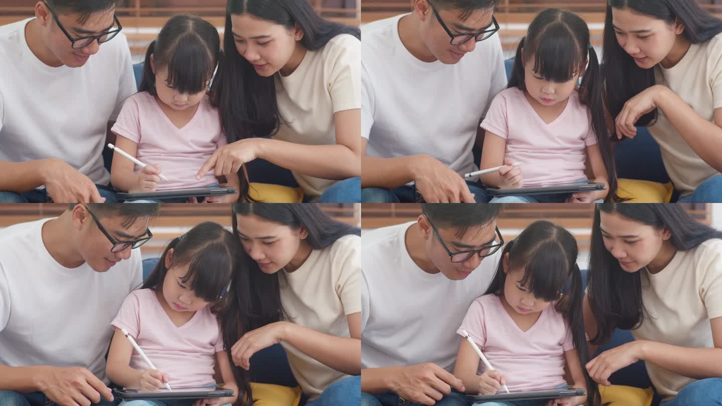 快乐的亚洲家庭爸爸，妈妈和女儿在客厅里用电脑平板技术坐在沙发上。自我隔离、待在家里、与他人保持距离、