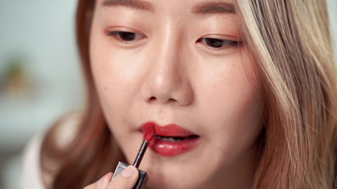 慢动作特写视频，漂亮的亚洲女人正在用漆刷，在嘴边涂口红
