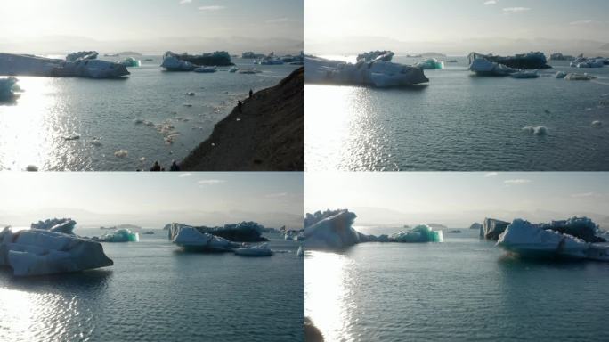 浮在水面上的冰块。阳光下的景色。飞越靠岸的人们，观看令人惊奇的自然景观。冰岛