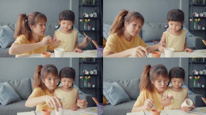 快乐快乐的亚洲家庭妈妈教蹒跚学步的小女孩画瓷壶在客厅的桌上玩乐放松。在一起度过的时间、社会距离、检疫