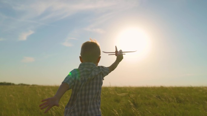 快乐的孩子，男孩，在阳光下奔跑，在夏天的田野里玩着玩具飞机。那孩子驾驶着一架玩具飞机。儿子梦想着飞行