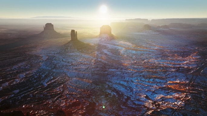 太阳直接照进相机，在无尽的沙漠纪念碑山谷上方到达地平线