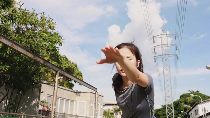 在跑步和戴耳机听音乐之前，年轻的亚洲女子在街上伸展腿和取暖是一种慢跑锻炼的生活方式。健康的生活方式.