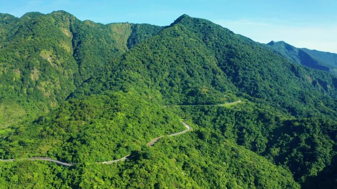 穿过绿林和高山的乡村道路的空中景观