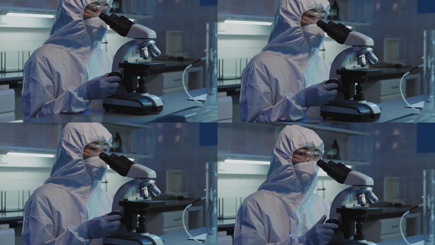 身着防护服、戴口罩、戴护目镜、戴着手套的女科学家在实验室用显微镜对着镜头看的慢镜头肖像画