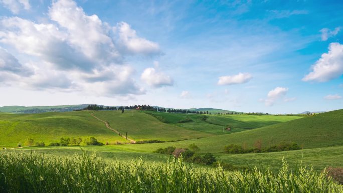 时间流逝：意大利托斯卡纳沃尔特拉地区独特的绿色景观。云彩在风中飘扬.在耕地和麦田上空的夕阳西下.