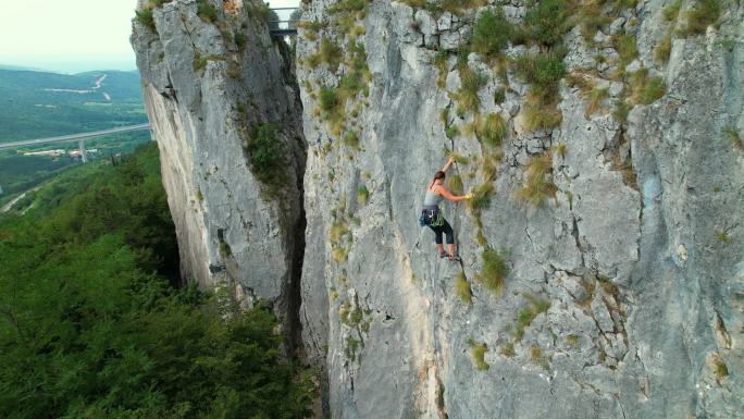 复制空间:俯瞰女性攀岩者爬上具有挑战性的悬崖的场景