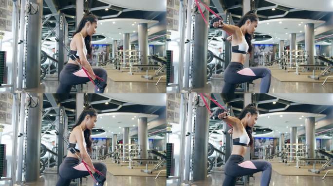 年轻的亚洲女士在健身课上做运动机械电缆交叉体脂燃烧锻炼。运动员六包，女运动员娱乐活动，功能性训练，健
