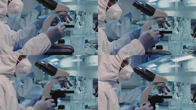 穿一次性工作服、戴口罩、戴护目镜和戴手套的无法辨认的黑人流行病学家在实验室显微镜下对他们进行了近距离