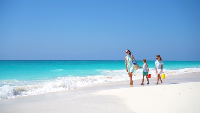 在白沙滩上散步的母亲和孩子的家人