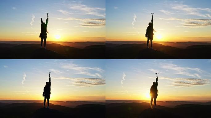 一位年轻的女登山者在日落时站在山顶上胜利地举起双手.