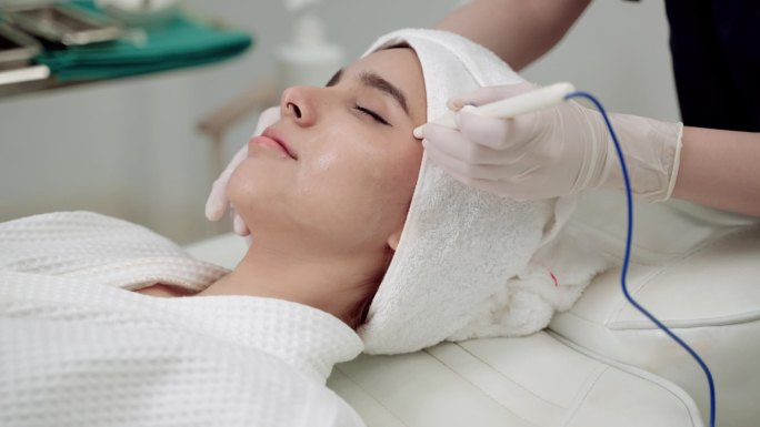 美容院，美女正在治疗她的脸。临床医生或护士使用美容诊所面部处理皮肤的工具加工.医生进行面部整容.